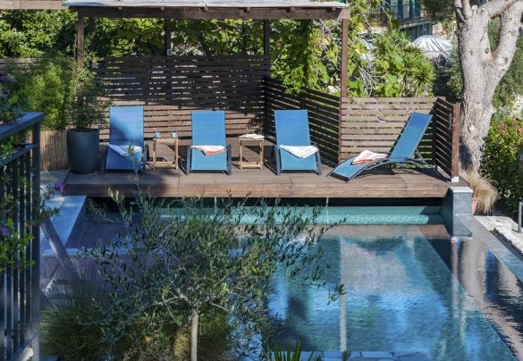 Una piattaforma solarium in legno teak, coperta da una tettoia, è accessoriata con lettini e tavolini - Villa nel Blu