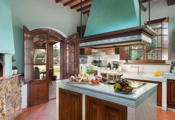 La cucina con forno a legna con accesso, tramite porta finestra, al patio con zona pranzo esterna – Villa Nikka