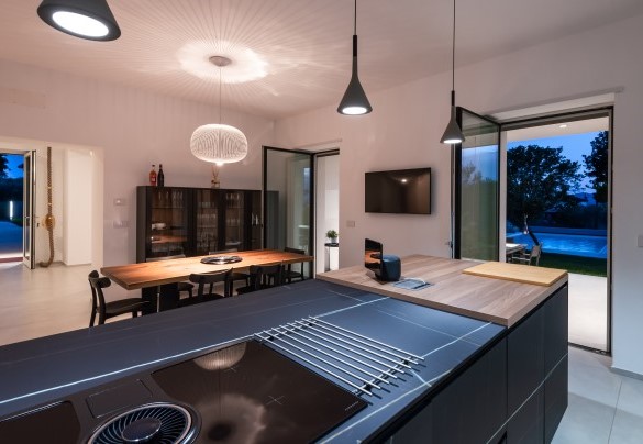 Glimpse of the kitchen and dining area with direct access to the outside at dusk – Villa Petrillo