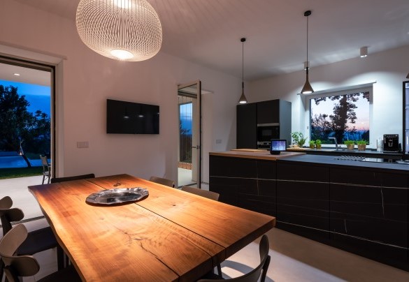 Glimpse of the kitchen and dining area with direct access to the outside at dusk – Villa Petrillo
