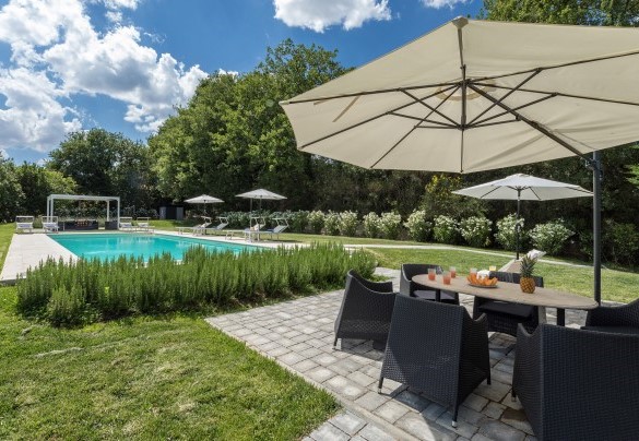 Ombrellone e tavolo da pranzo nel solarium in pietra della piscina - Villa Pianello