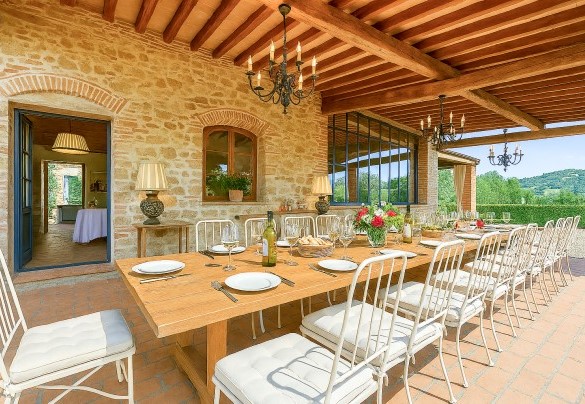 Il porticato all'uscita della cucina ospita un tavolo con sedie per pranzi all'aperto - Villa Ginevra