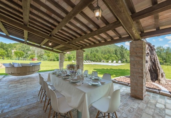 Lo spazioso portico raggiungibile dalla sala pranzo, elegantemente arredato con tavolo, sedie e una suggestiva amaca matrimoniale sospesa – Villa Poderina 