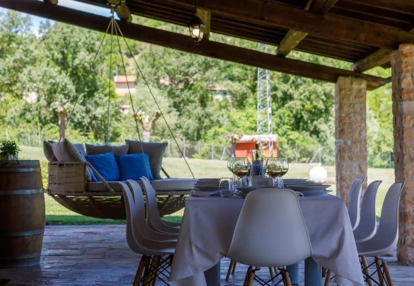 Lo spazioso portico raggiungibile dalla sala pranzo, elegantemente arredato con tavolo, sedie e una suggestiva amaca matrimoniale sospesa – Villa Poderina