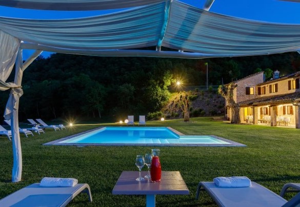 Lungo il perimetro della vasca si sviluppa l’area solarium, a prato, arredata con lettini – Villa Poderina