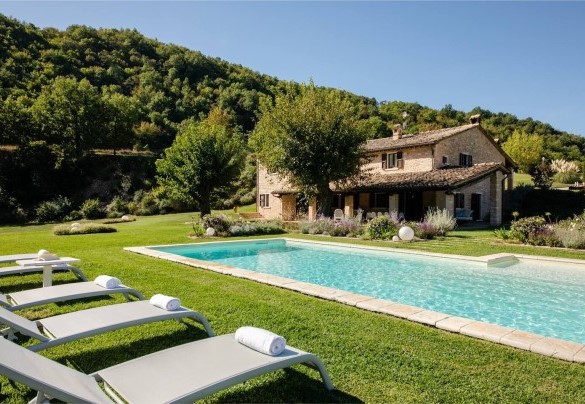 Lungo il perimetro della vasca si sviluppa l’area solarium, a prato, arredata con lettini – Villa Poderina