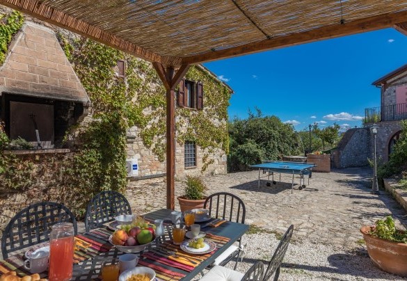 La zona pranzo esterna sotto la pergola, allestita con tavolo e sedie - Villa Poggiente
