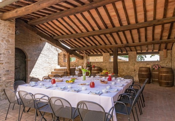 La corte davanti all’ingresso principale, all’ombra di un porticato è allestita la zona pranzo con tavoli e sedie- Villa Poggio Bonelli