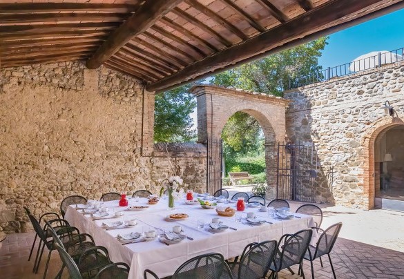 La corte davanti all’ingresso principale, all’ombra di un porticato è allestita la zona pranzo con tavoli e sedie- Villa Poggio Bonelli