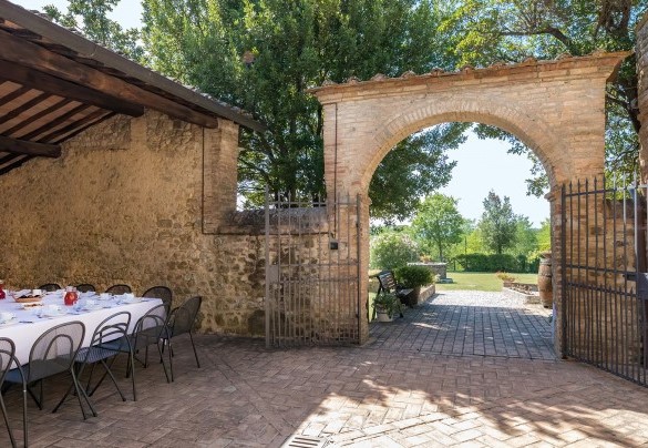 La corte davanti all’ingresso principale, all’ombra di un porticato è allestita la zona pranzo con tavoli e sedie- Villa Poggio Bonelli