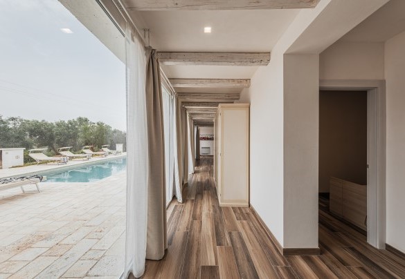 Il lungo corridoio che separa le camere ha ampie vetrate che affacciano sulla piscina – Villa Puspo