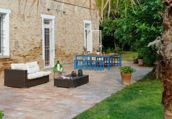  Nella zona pavimentata perimetrale, troviamo un bellissimo tavolo dove è possibile consumare pranzi o cene all’aperto e un comodo divano con poltrone e tavolino dove godersi splendidi aperitivi serali – Villa Rustica