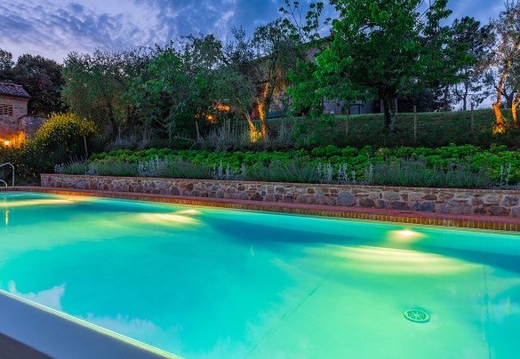 La piscina illuminata e il casale nei bagliori del tramonto – Villa Santa Maria