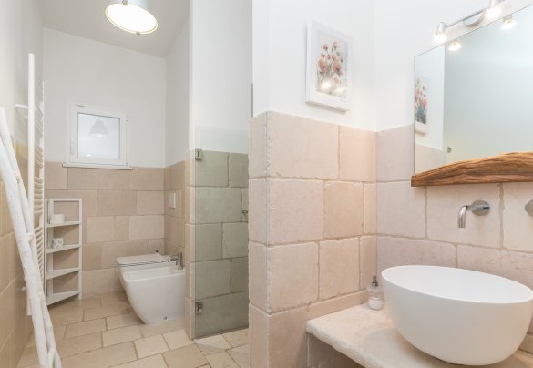 Bagno con doccia n.2 con rivestimento in pietra e dettagli in legno di ulivo - Villa Soleluna