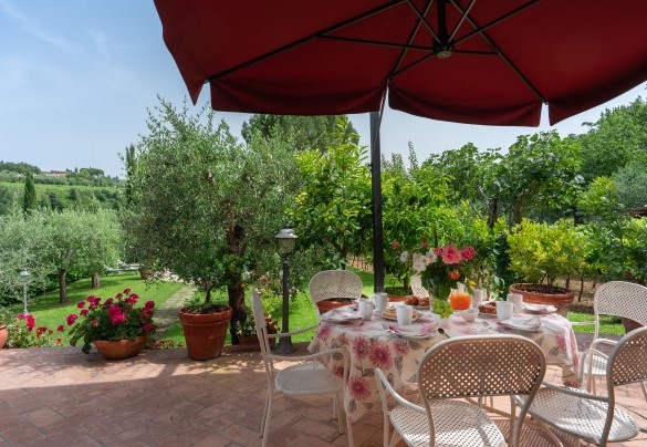 La zona pranzo esterna corredata di ombrellone e di barbecue in pietra all'uscita del salotto - Villa Sorripa