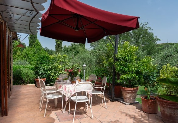 La zona pranzo esterna corredata di ombrellone e di barbecue in pietra all'uscita del salotto - Villa Sorripa