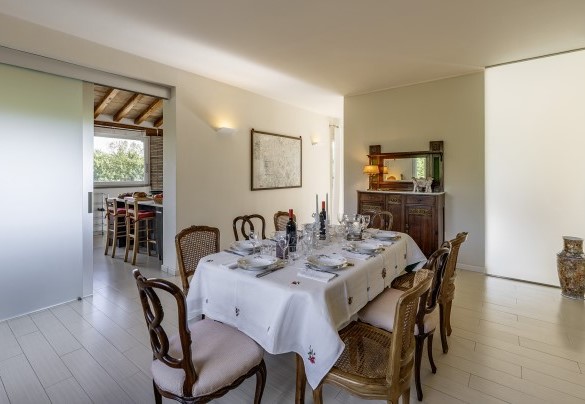 The dining room connects to the kitchen, living room, bedroom n.1, and is served by a guest bathroom - Villa Sparta