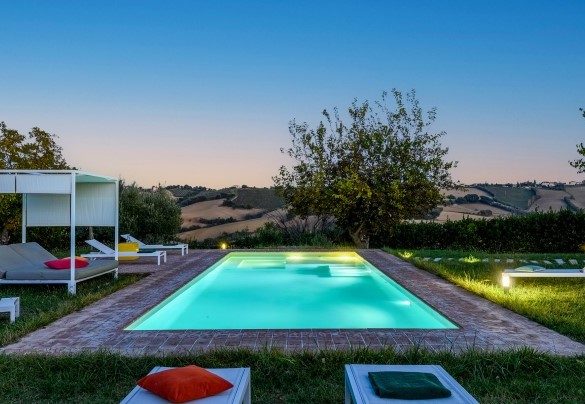 Illuminated pool with relaxation area and garden view – Villa Traiani