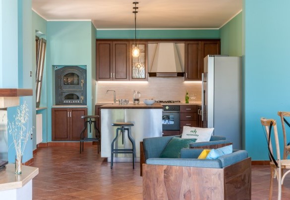 Equipped kitchen with wood oven and island with stools – Villa Traiani