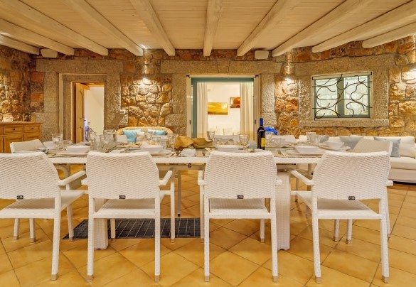 Living esterno impreziosito da travi in legno bianco con elegante tavola in cui trascorrere piacevoli serate estive – Villa Typha