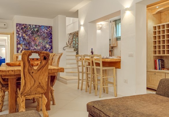 Zona living del piano seminterrato con tavolo in legno e divani – Villa Typha