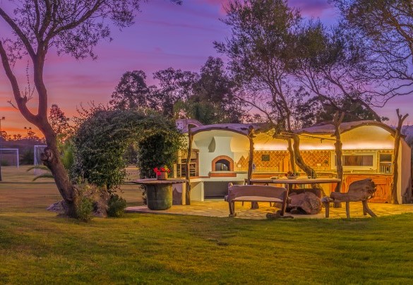 Cucina esterna illuminata e incorniciata da suggestivi colori del tramonto – Villa Typha
