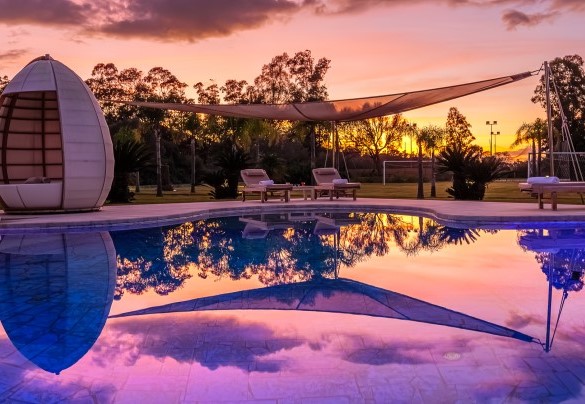 Suggestivo tramonto sull’elegante piscina bordata da pavimentazione in marmo di Orosei  - Villa Typha