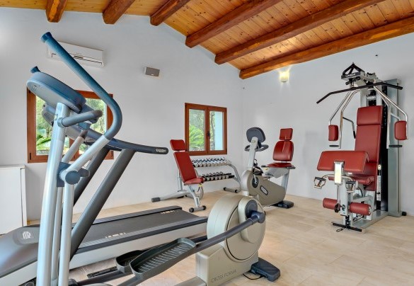 Area fitness coperta dotata di ellittica, panca per pesi, tapis roulant, cyclette, panca per addominali e pesi – Villa Typha
