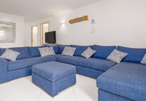 Seconda zona living del piano seminterrato con divano e tv ha accesso diretto al giardino tramite 5 gradini – Villa Typha