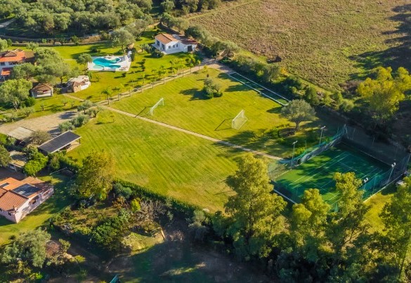 Vista aerea del grande parco privato, armoniosamente animato da piante autoctone e palme esotiche che ospita la lussuosa piscina interamente rivestita in marmo di Orosei , il campo da calcio, il campo da bocce e il campo da tennis – Villa Typha