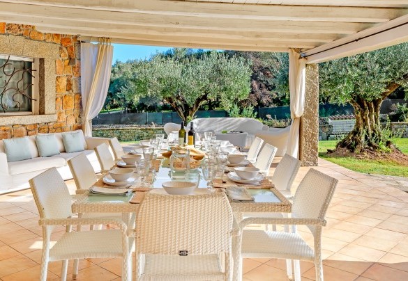 Living esterno impreziosito da travi in legno bianco con vista sulla piscina – Villa Typha