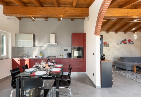 The large open-plan environment includes the large and bright living room with the sofa bed and the masonry fireplace, the dining area and the kitchenette - Villa Vittorio