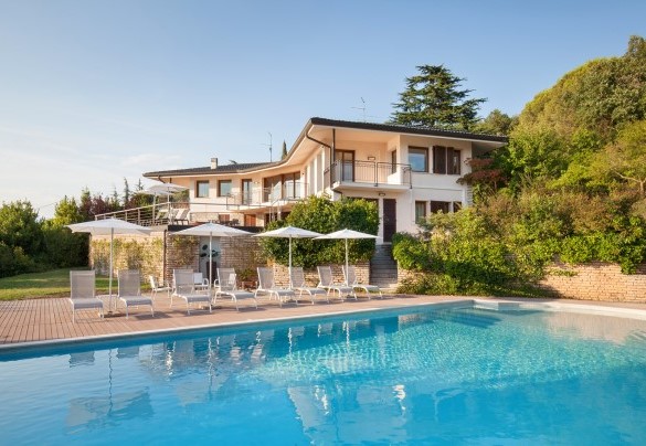 The pool features a sunbathing area with loungers and umbrellas - Villa Viù