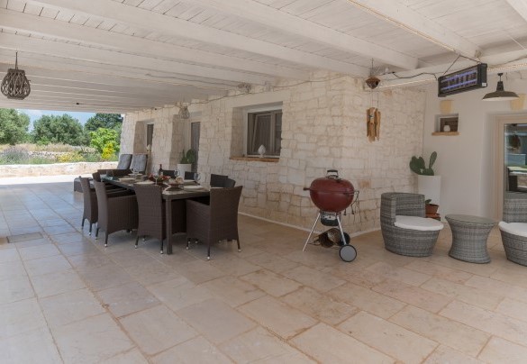 Il grande porticato esterno di fronte alla piscina, con area pranzo e piccolo living – White Stone House